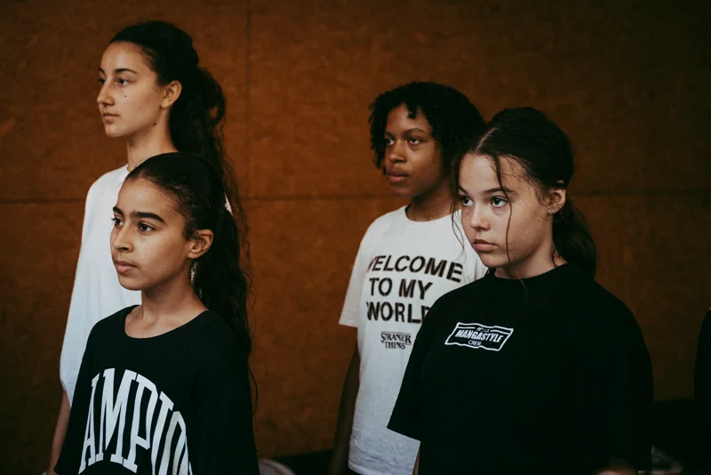 Quatre danseuses concentrées, t-shirts Mangastyle et Stranger Things, lumière chaude